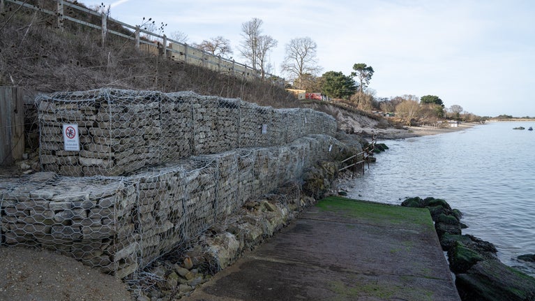 Sea defences made of stones in wire baskets, sea lapping against them.